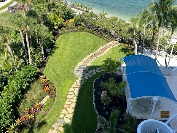 Coastal backyard landscape with lawn and tropical plantings above the water