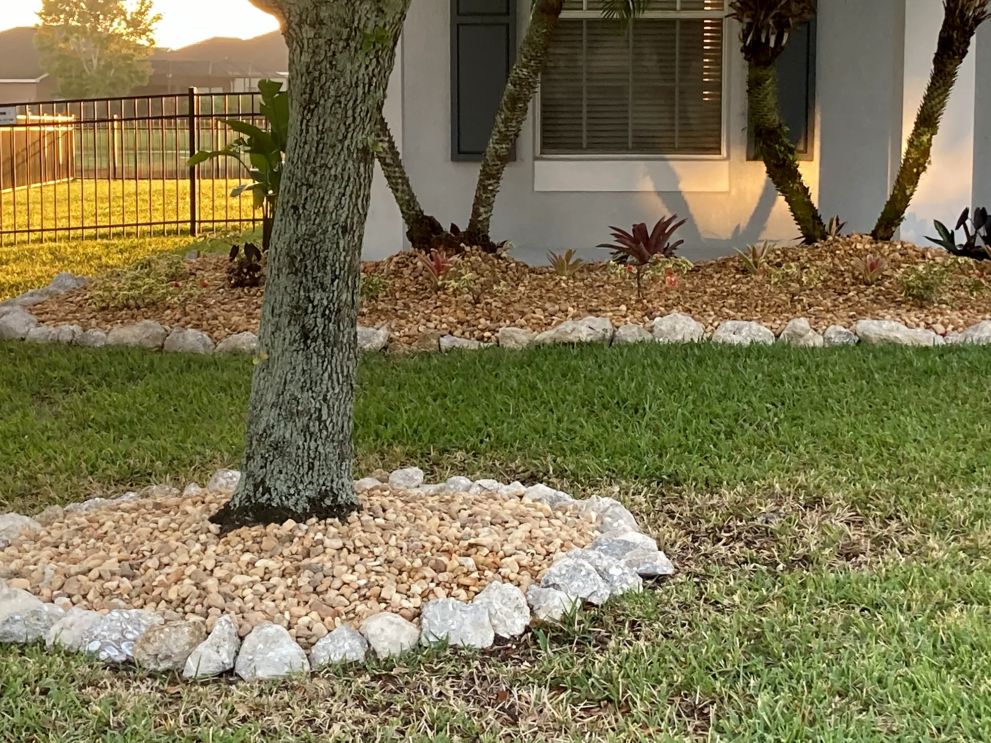 Tree ring of white river rock edged with stone in a front lawn