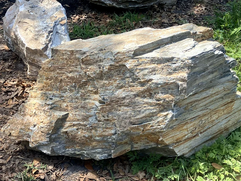 Large layered boulder set in a landscape bed