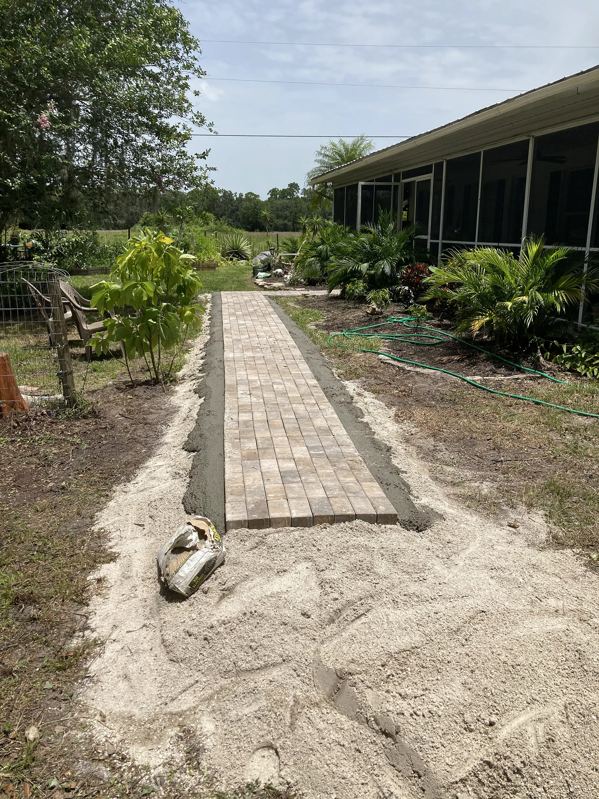Paver walkway being laid on a sand base beside a screened lanai