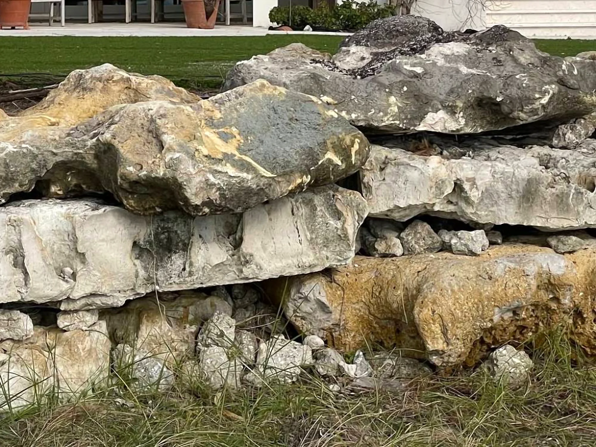 Stacked natural boulder retaining wall in front of a lawn