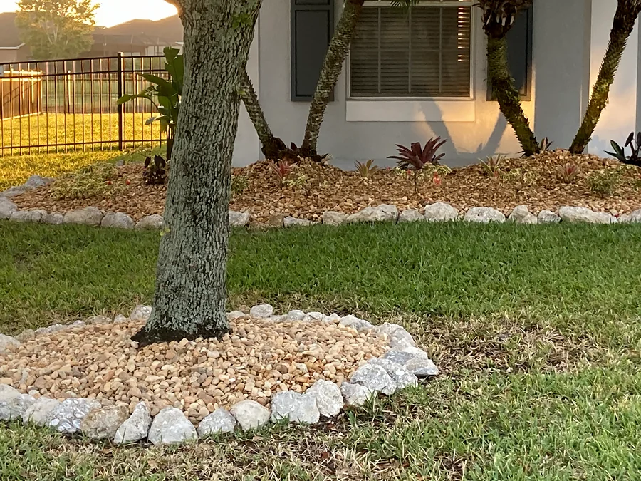 Tree ring of river rock edged with white stone in a front lawn